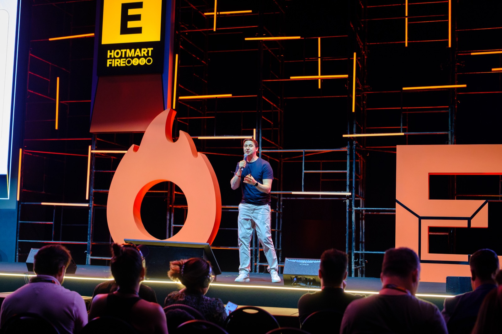 Adriano Gianini palestrando no palco do Hotmart FIRE 2026, com a plateia em primeiro plano
